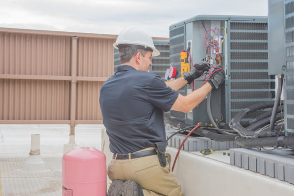 hvac technician performing an ac tune-up on outdoor unit